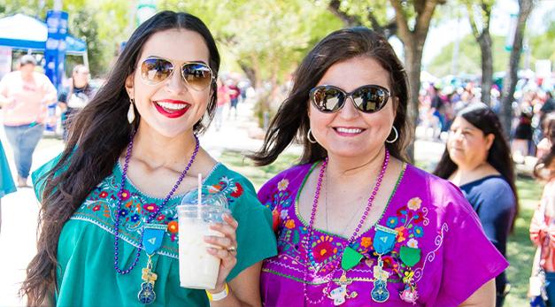 Two women wearing fiesta medals and smiling